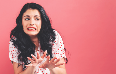 A woman makes a grossed-out facial expression in response to something she's seeing.